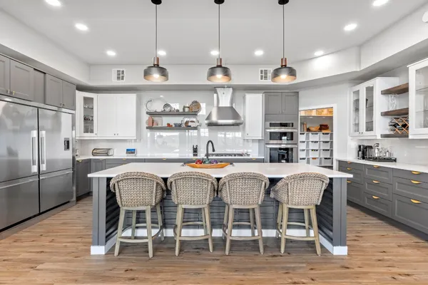 a kitchen with stainless steel appliances granite countertop a dining table chairs refrigerator and microwave