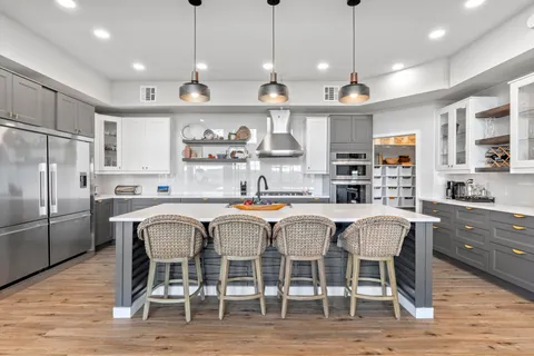 a kitchen with stainless steel appliances granite countertop a dining table chairs refrigerator and microwave