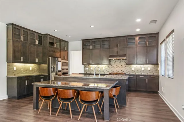 a kitchen with granite countertop kitchen island stainless steel appliances a sink and cabinets