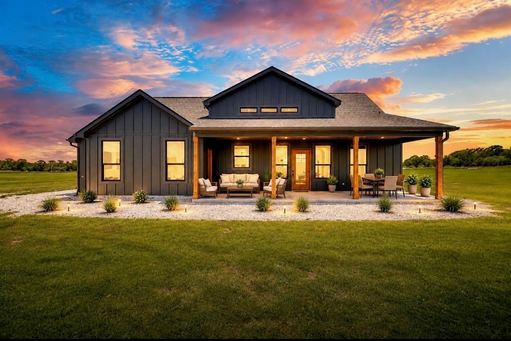 Contemporary exterior with dark vertical siding, a covered concrete patio, and a wood-paneled entry door