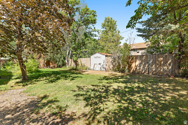 658 Wasatch Street Midvale, UT 84047 - Photo 24 of 31 Expansive grassy yard with a storage shed, mature trees, and a wood privacy fence
