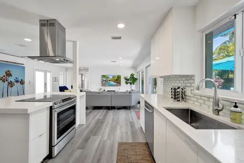 a kitchen with stainless steel appliances granite countertop a sink a stove and a wooden floors