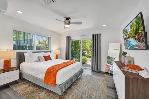 a bedroom with a bed a dresser and a large window