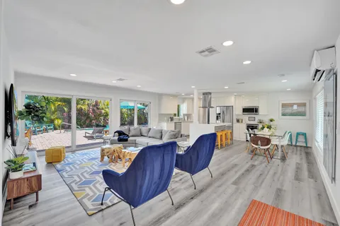 a living room with furniture dining table wooden floor and a large window