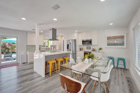 a living room with stainless steel appliances furniture a dining table and kitchen view