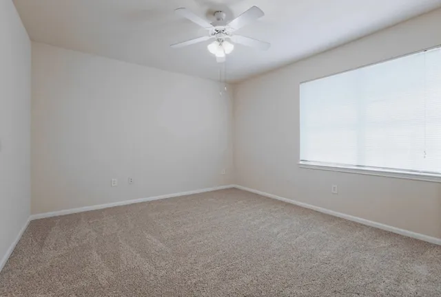 an empty room with a window and a fan