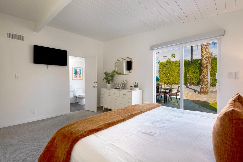 302 East Racquet Club Road Palm Springs, CA 92262 - Photo 17 of 38 a bedroom with a bed and a flat screen tv