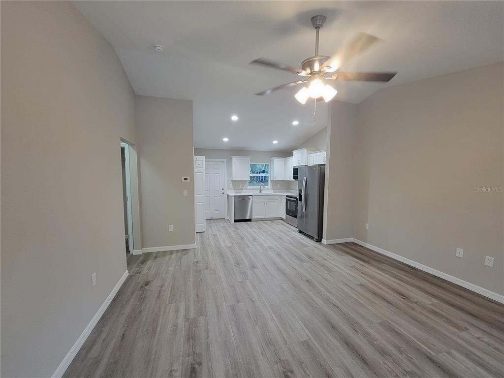 3150 Southwest 96th Place, Unit 1 Ocala, FL 34476 - Photo 3 of 8 a view of a room with wooden floor a ceiling fan and kitchen