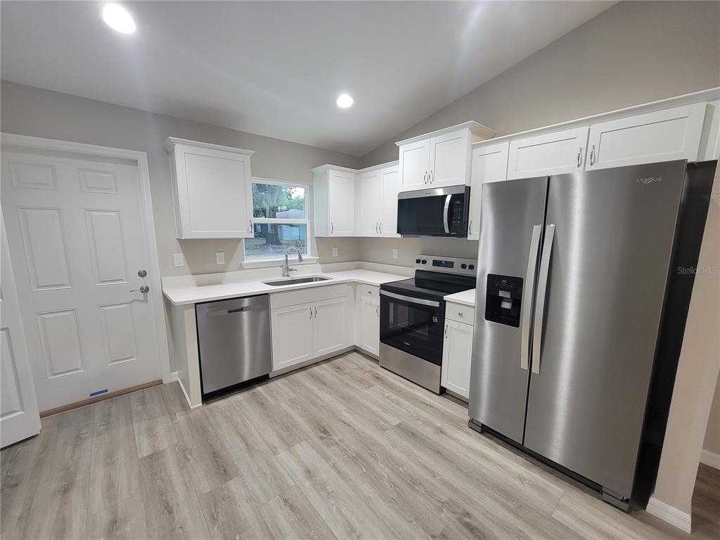 3150 Southwest 96th Place, Unit 1 Ocala, FL 34476 - Photo 4 of 8 a kitchen with a refrigerator sink and wooden floor