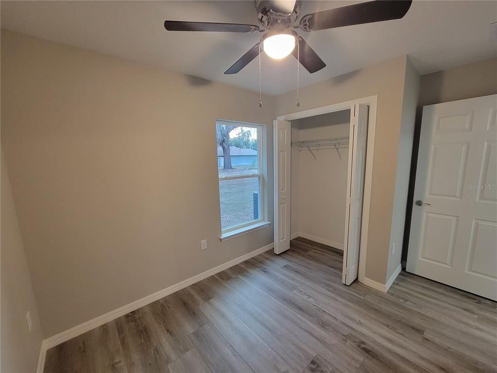 3150 Southwest 96th Place, Unit 1 Ocala, FL 34476 - Photo 6 of 8 an empty room with wooden floor fan and windows