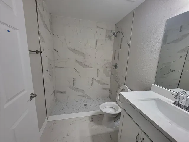 a bathroom with a granite countertop sink toilet and shower