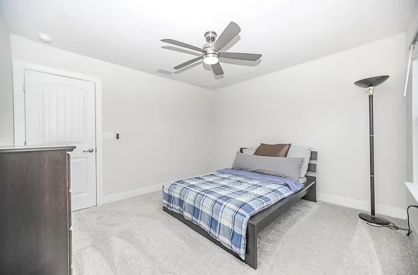 a living room with a bed and ceiling fan