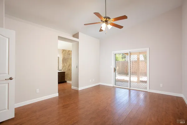 an empty room with wooden floor fan and windows
