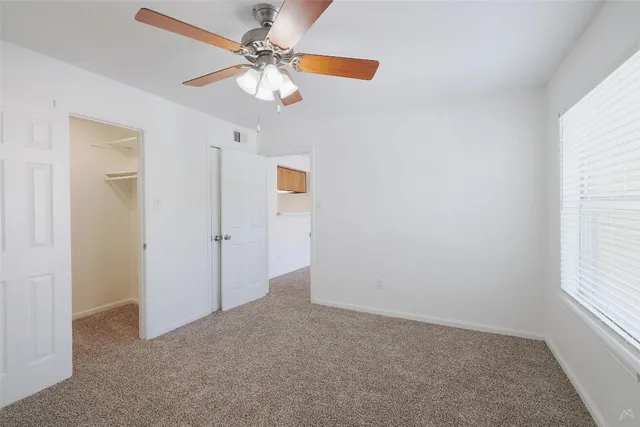 an empty room with a window and a fan
