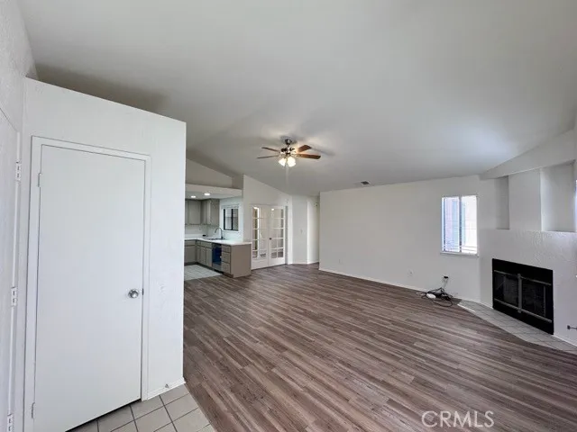an empty room with wooden floor fireplace and windows