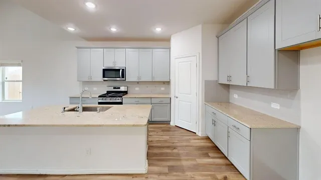 a kitchen with granite countertop white cabinets and stainless steel appliances