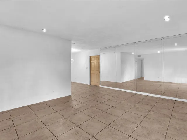 a view of an empty room with window and cabinet area