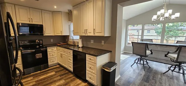 a kitchen with granite countertop a stove a sink dishwasher and a refrigerator with wooden floor