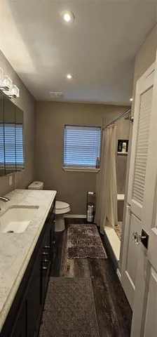 a spacious bathroom with a granite countertop sink a toilet a mirror and shower
