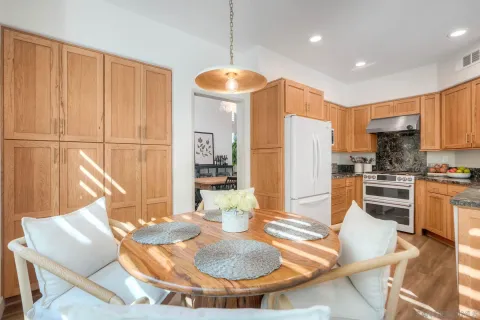 a kitchen with granite countertop a refrigerator a stove a sink dishwasher with a dining table and chairs