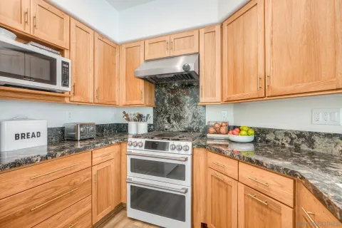 a kitchen with granite countertop white cabinets and stainless steel appliances