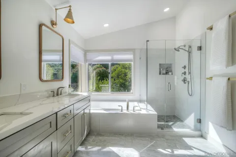 a bathroom with a granite countertop tub sink and mirror