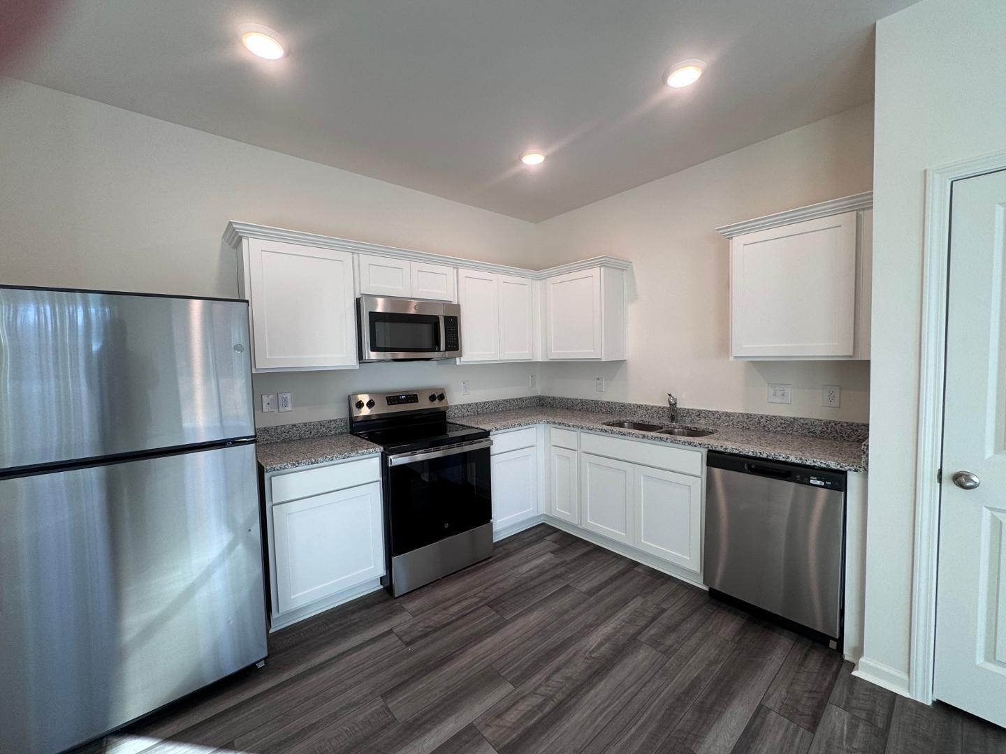 2002 Trailside Drive Durham, NC 27704 - Photo 8 of 14 a kitchen with granite countertop a refrigerator stove and wooden floor