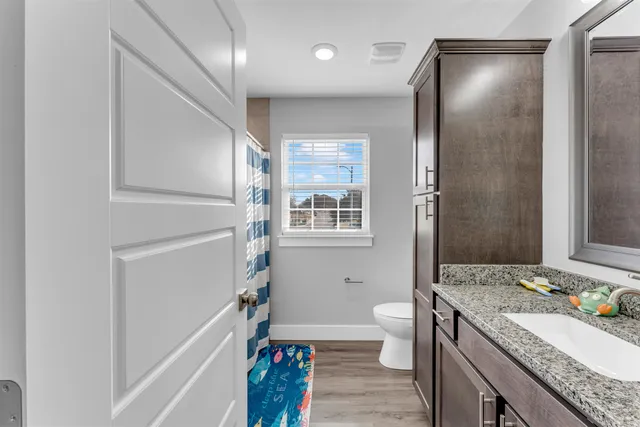 a bathroom with a granite countertop sink a toilet and shower