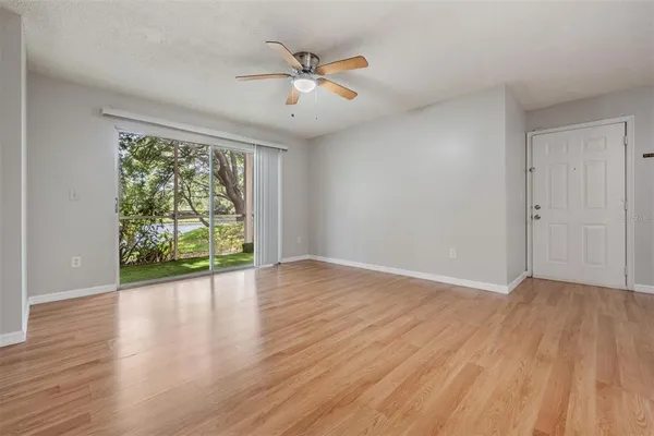 an empty room with wooden floor fan and windows