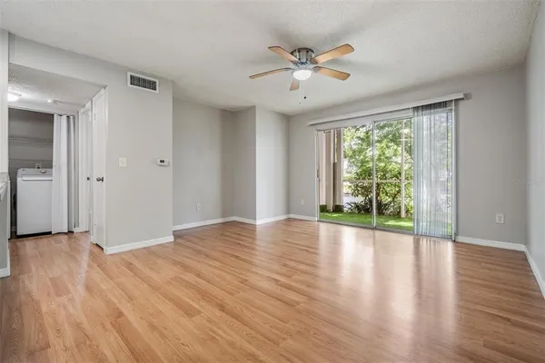 a view of an empty room with wooden floor and a window