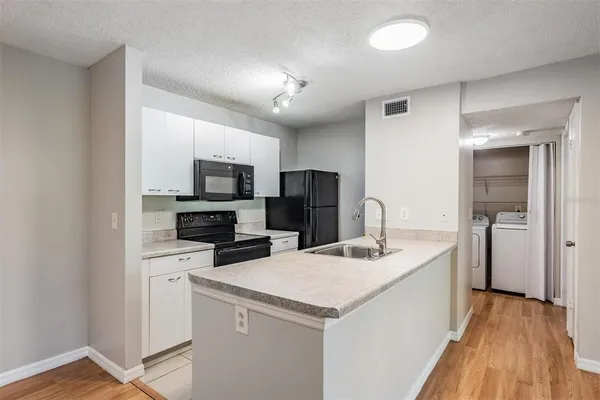 a kitchen with a sink a microwave a refrigerator and cabinets