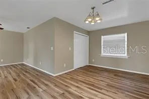a view of an empty room with window and chandelier fan