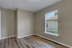 a view of an empty room with window and wooden floor