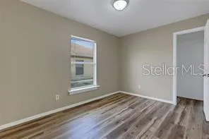 a view of an empty room with wooden floor and a window