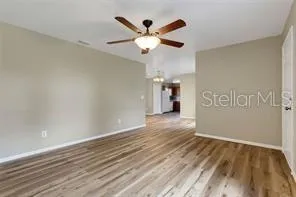 an empty room with wooden floor and ceiling fan