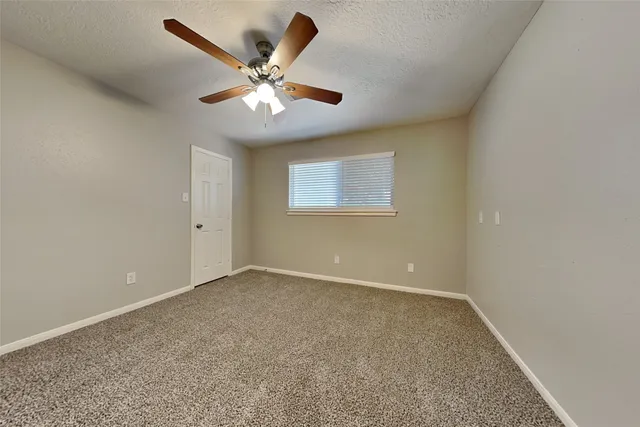 an empty room with a window and a fan