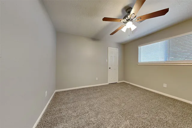 an empty room with a chandelier fan and windows