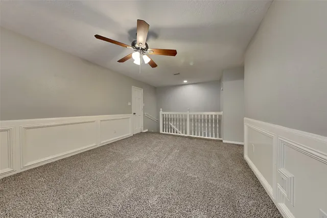 a view of an empty room and chandelier fan