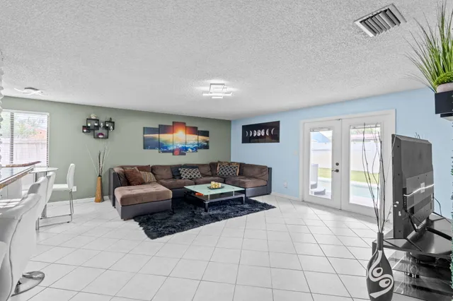 a living room with furniture a flat screen tv and a floor to ceiling window