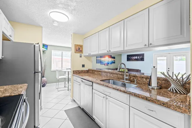 a kitchen with granite countertop a sink stainless steel appliances and white cabinets