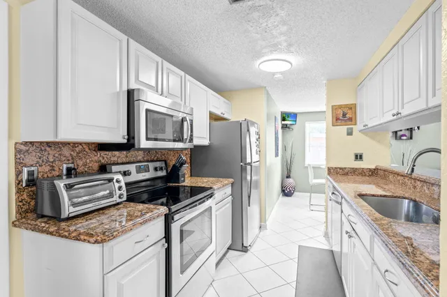 a kitchen with stainless steel appliances granite countertop a sink stove refrigerator and cabinets