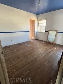 a view of a livingroom with an empty space & a window wooden floor