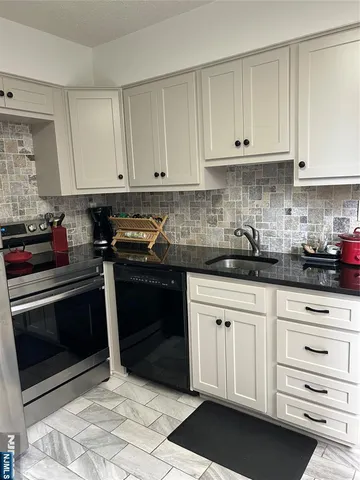 a kitchen with granite countertop white cabinets and stainless steel appliances