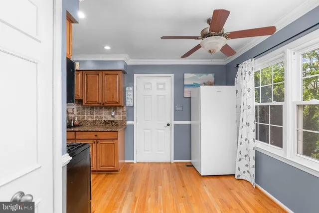 a kitchen with stainless steel appliances a refrigerator a sink dishwasher a stove and a dining table with wooden floor