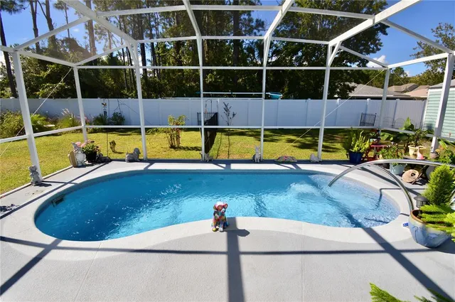 a view of a swimming pool with a patio and a yard