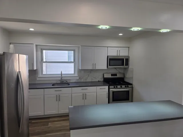 a kitchen with stainless steel appliances granite countertop a refrigerator a stove a sink and a microwave