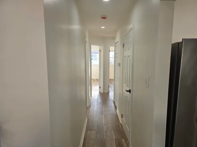 a view of a hallway with wooden floor and a bathroom
