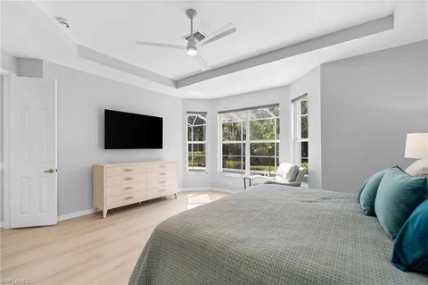 a large bedroom with a bed and a flat tv screen on dresser