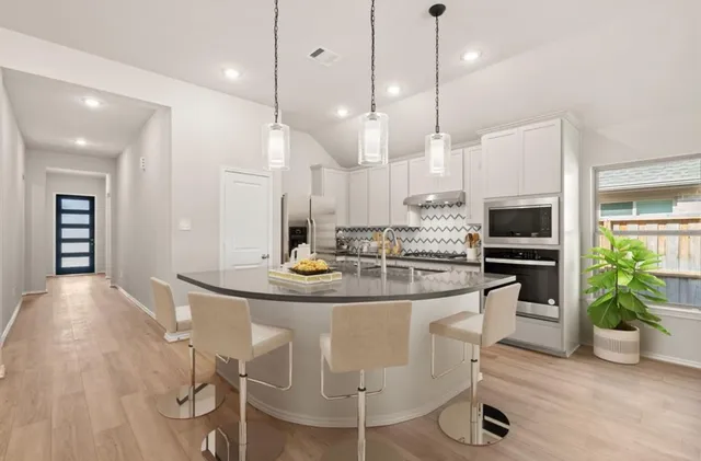 a kitchen with kitchen island a dining table chairs stainless steel appliances and cabinets