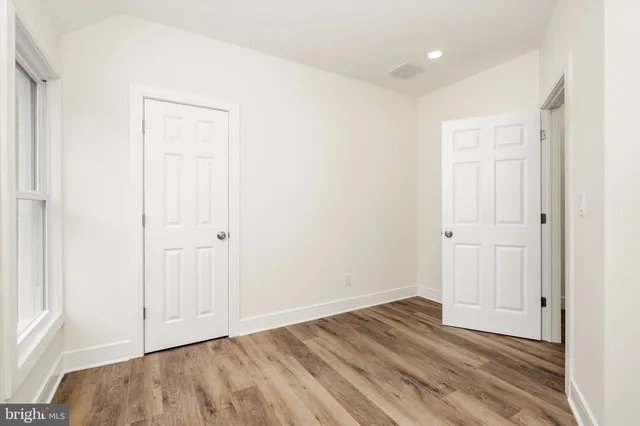 an empty room with wooden floor and closet area